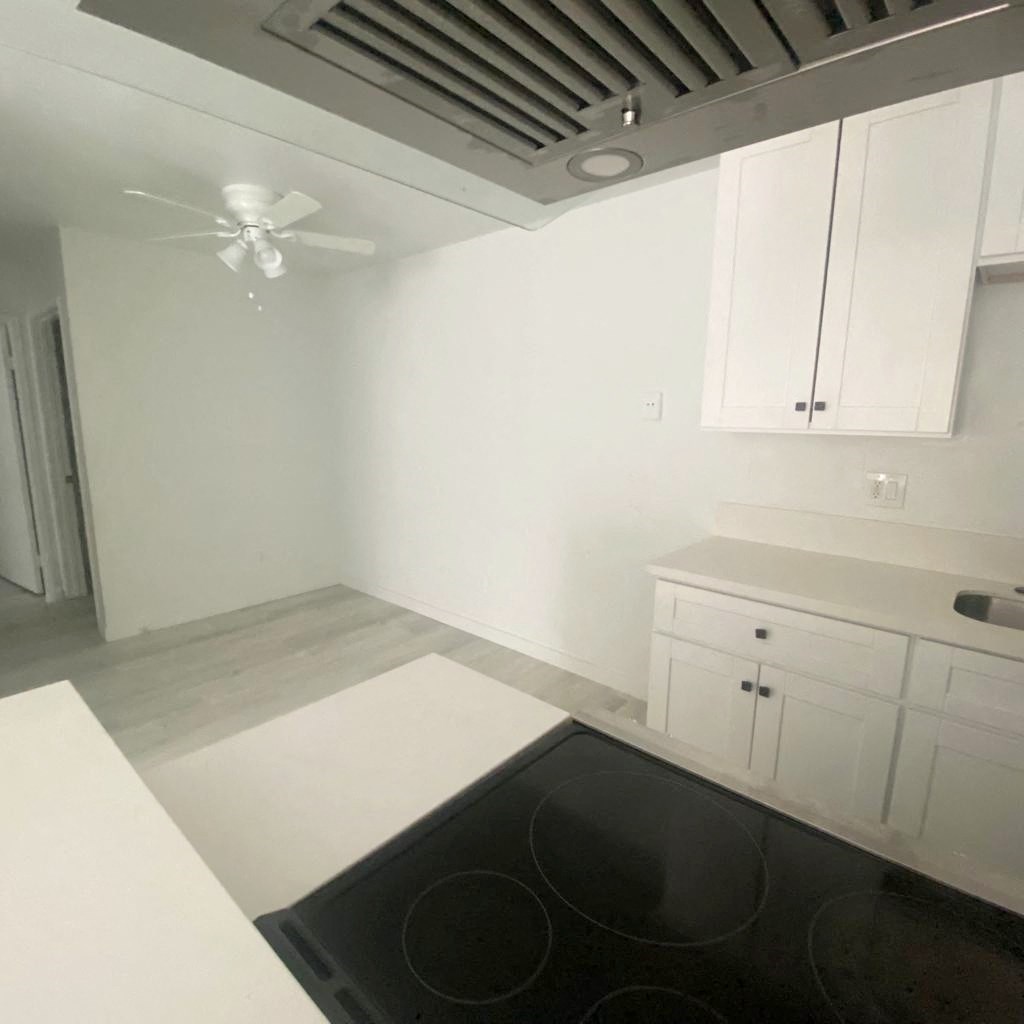 an empty kitchen with white cabinets and a black stove