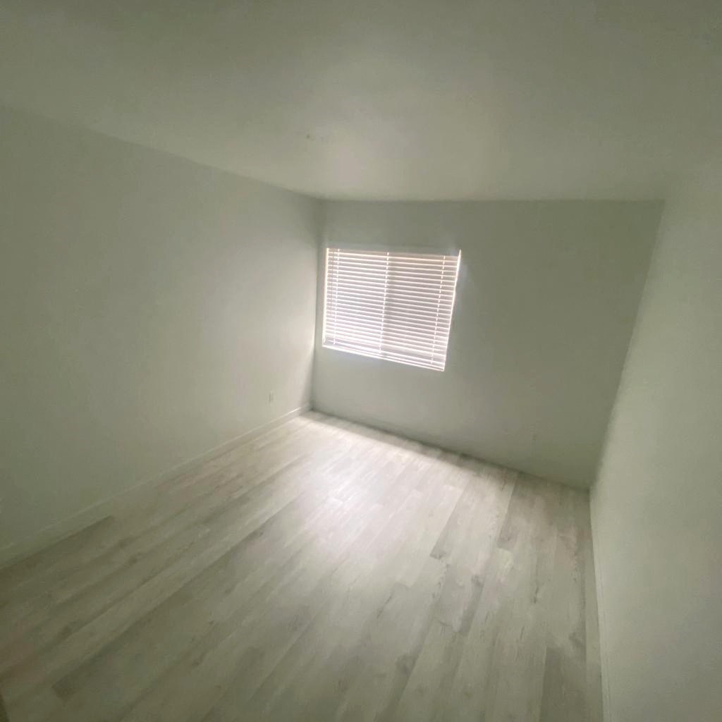 an empty room with wooden floors and a window