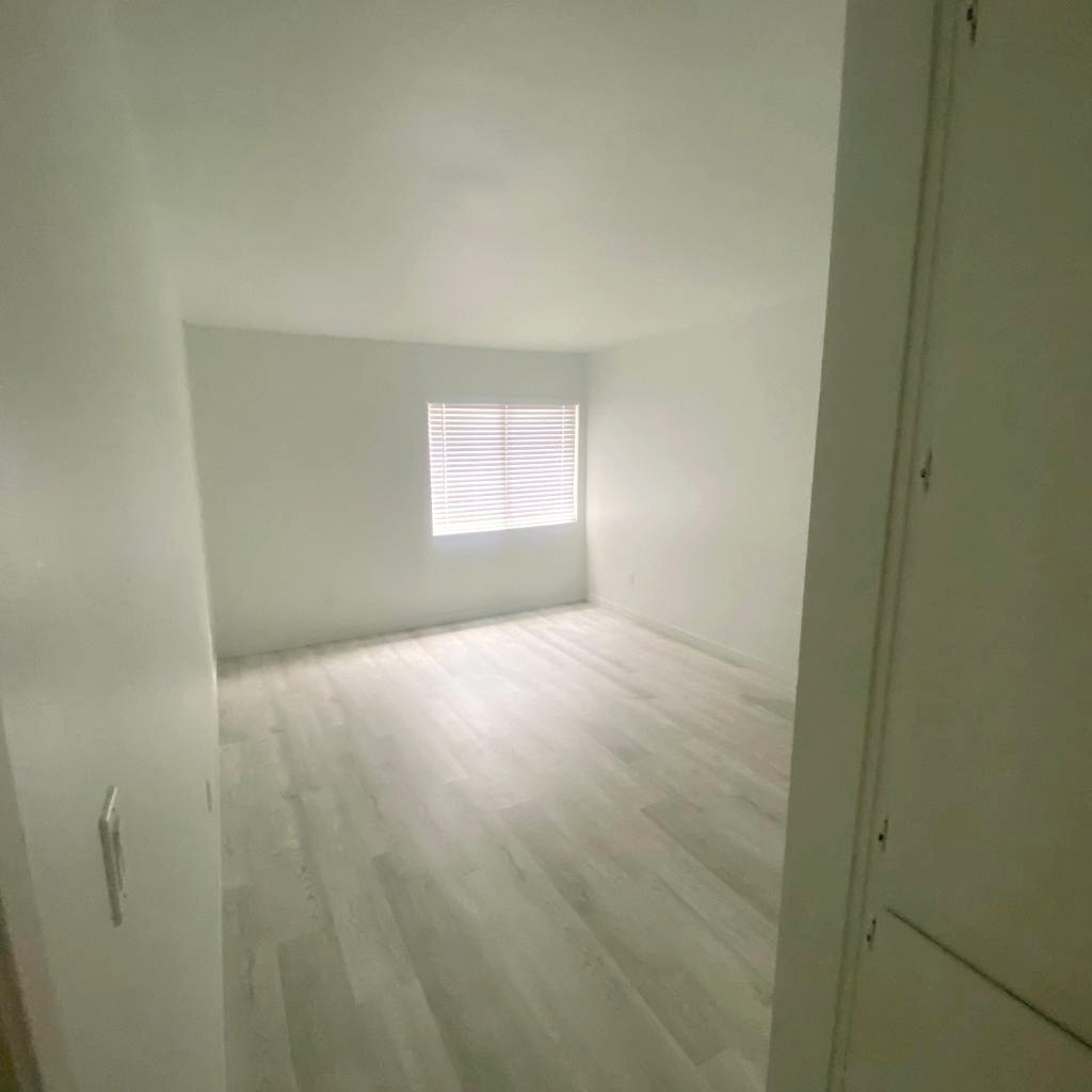 an empty room with wooden floors and a window