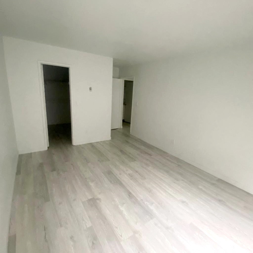 an empty living room with white walls and wooden floors