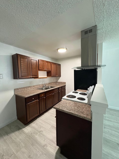 A kitchen with brown cabinets and a granite countertop.