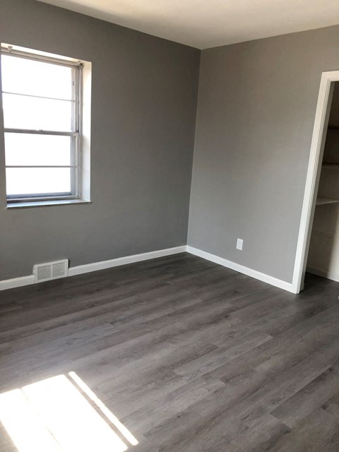 an empty room with wooden floors and a window