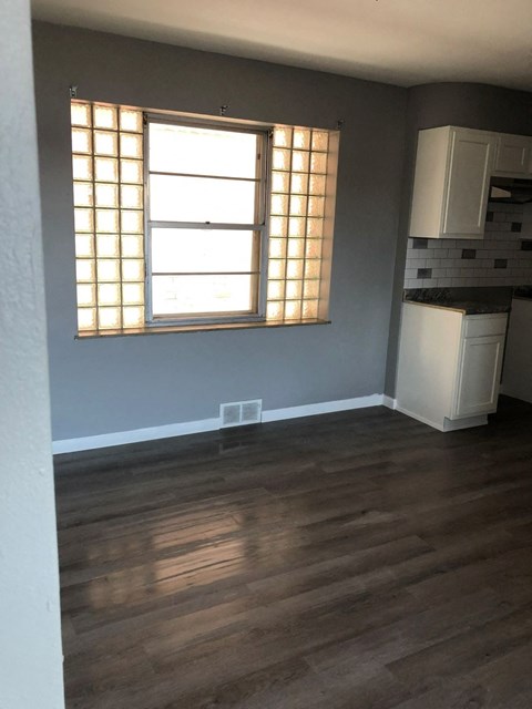 an empty living room with wood floors and a window