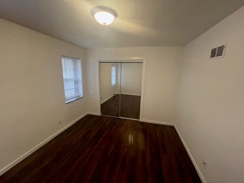 an empty room with a hard wood floor and a window