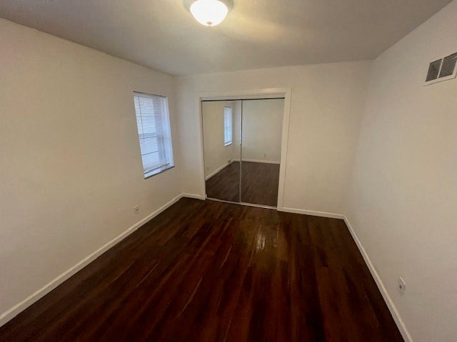 an empty living room with a hard wood floor and a window