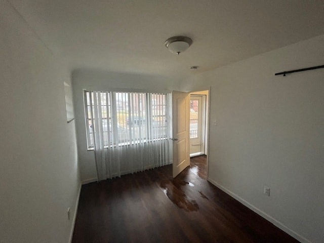 an empty living room with a wood floor and a window