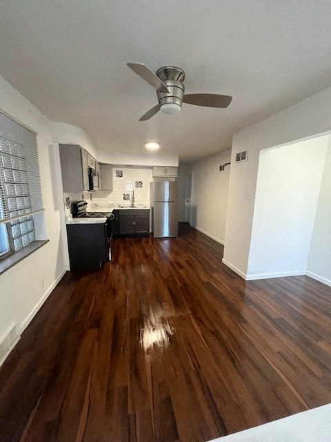 an empty living room with wood floors and a ceiling fan