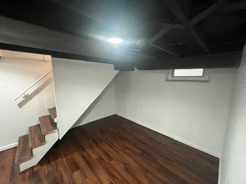 an empty room with a wood floor and stairs