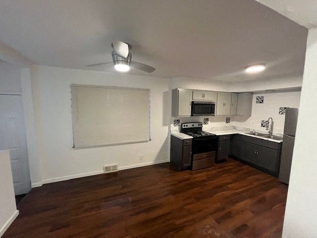 an empty kitchen with a wood floor and black appliances