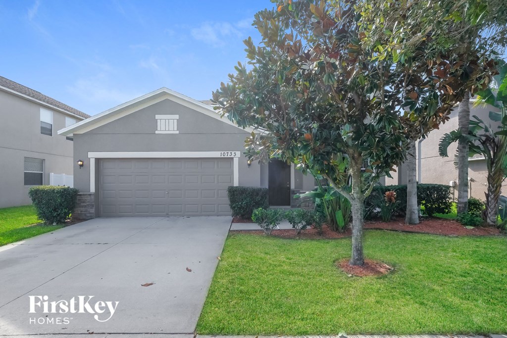 a home with a driveway and a tree in front of it