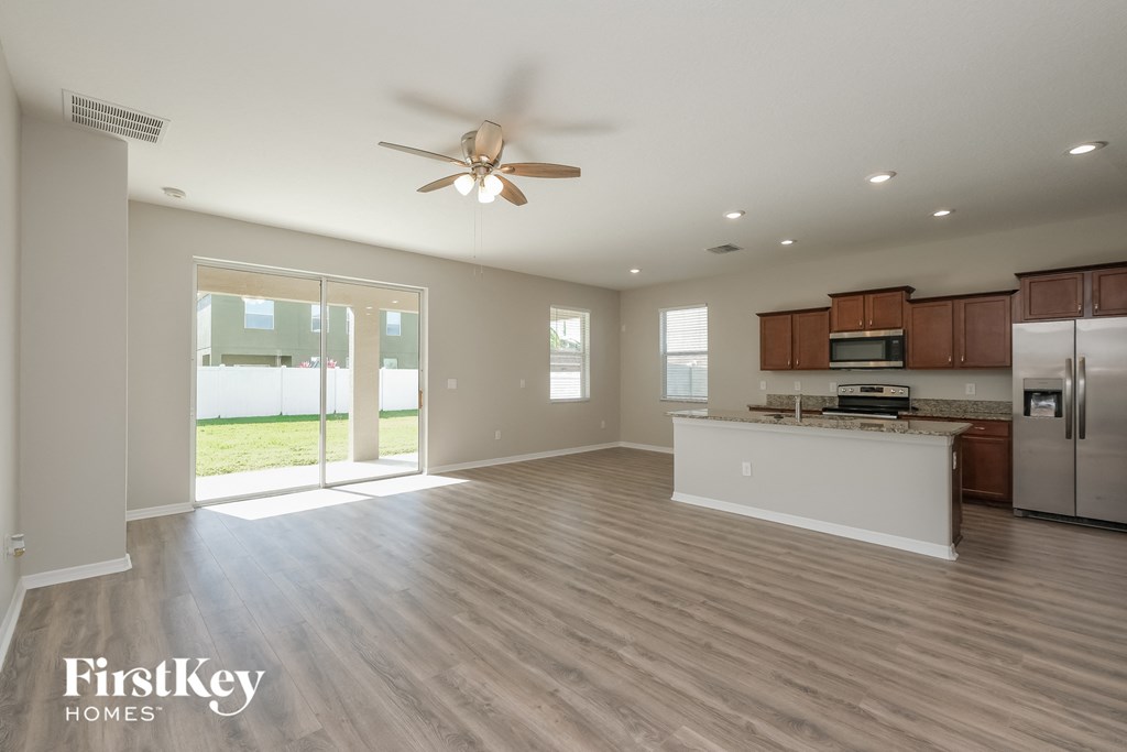 a spacious living room with a kitchen and a ceiling fan