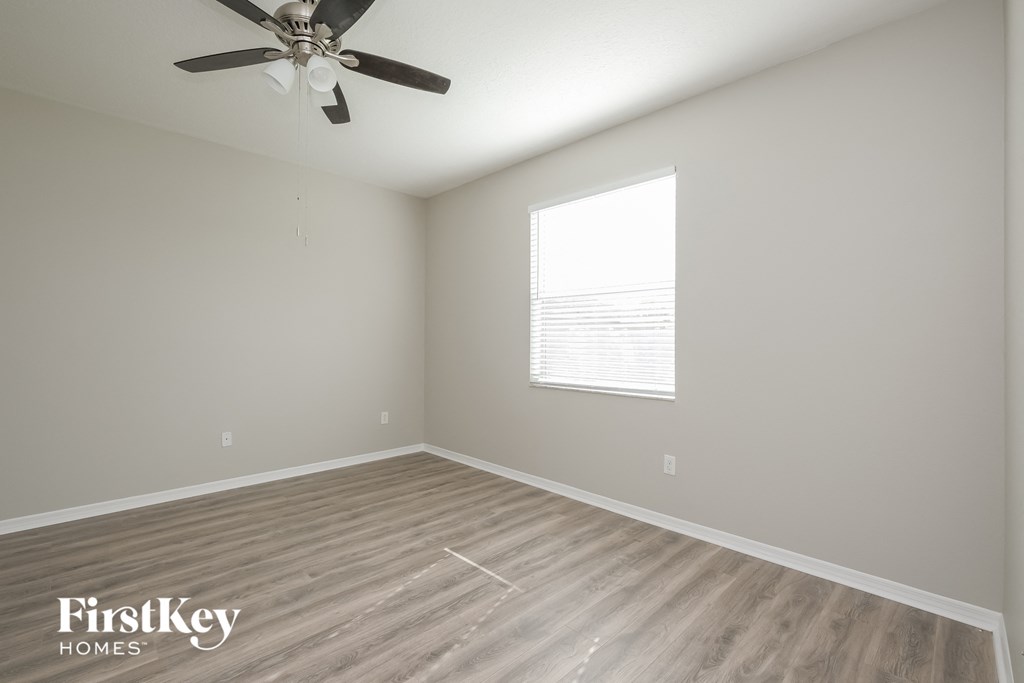 an empty room with a ceiling fan and a window