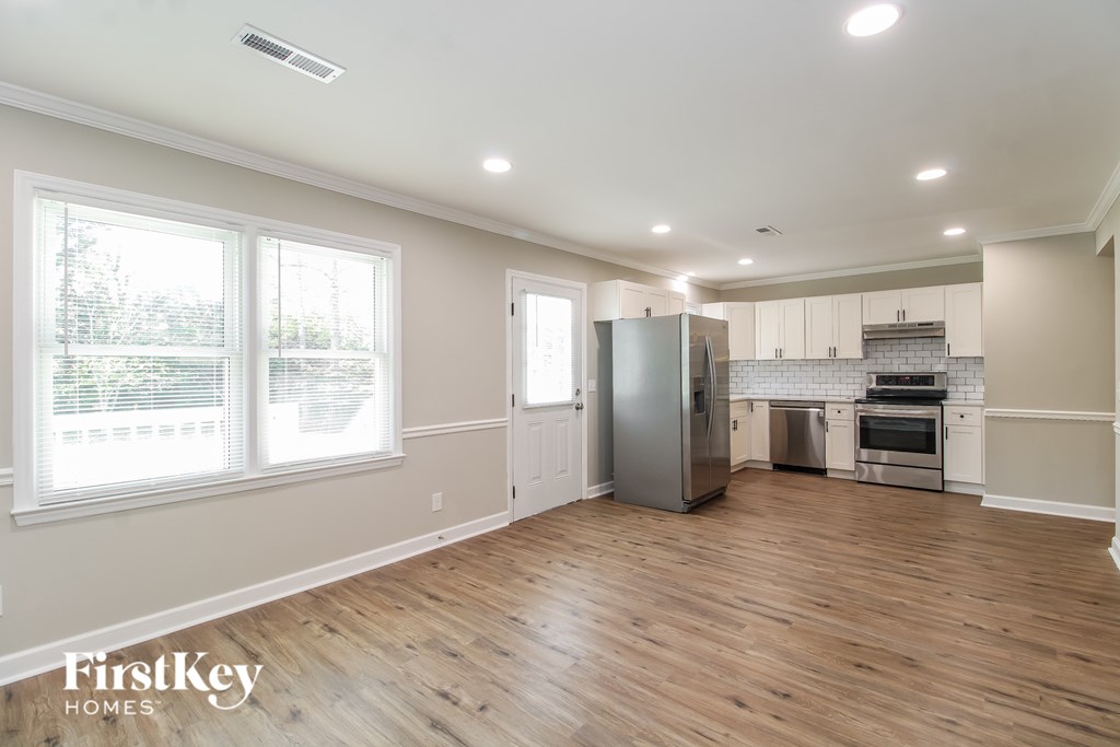 A kitchen with wooden floors and a refrigerator in the middle.