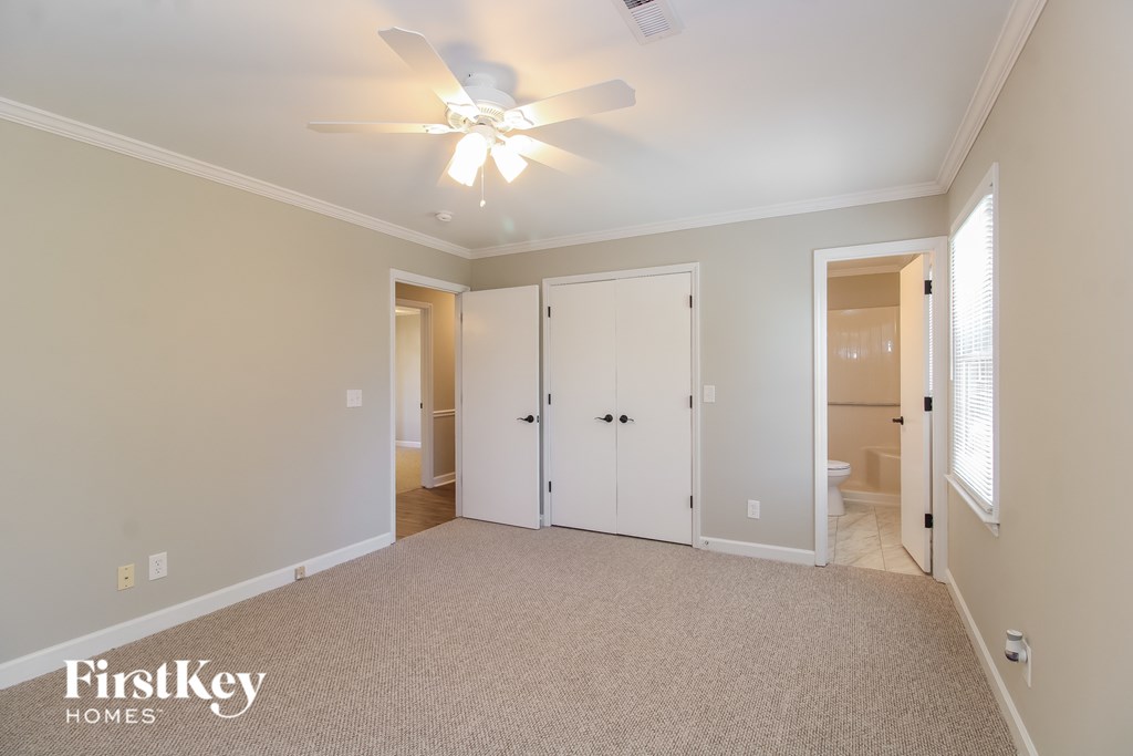 A spacious room with a ceiling fan and carpeted floor.