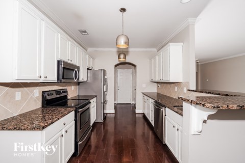 a large kitchen with white cabinets and granite counter tops