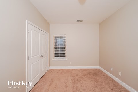 a bedroom with carpet and a door to a closet