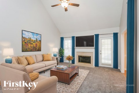 A living room with a beige couch, a coffee table, a fireplace, and a painting on the wall.