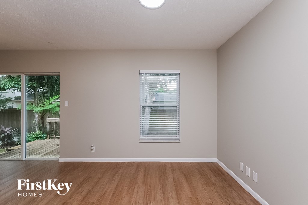 the living room of an empty house with wood floors and a window