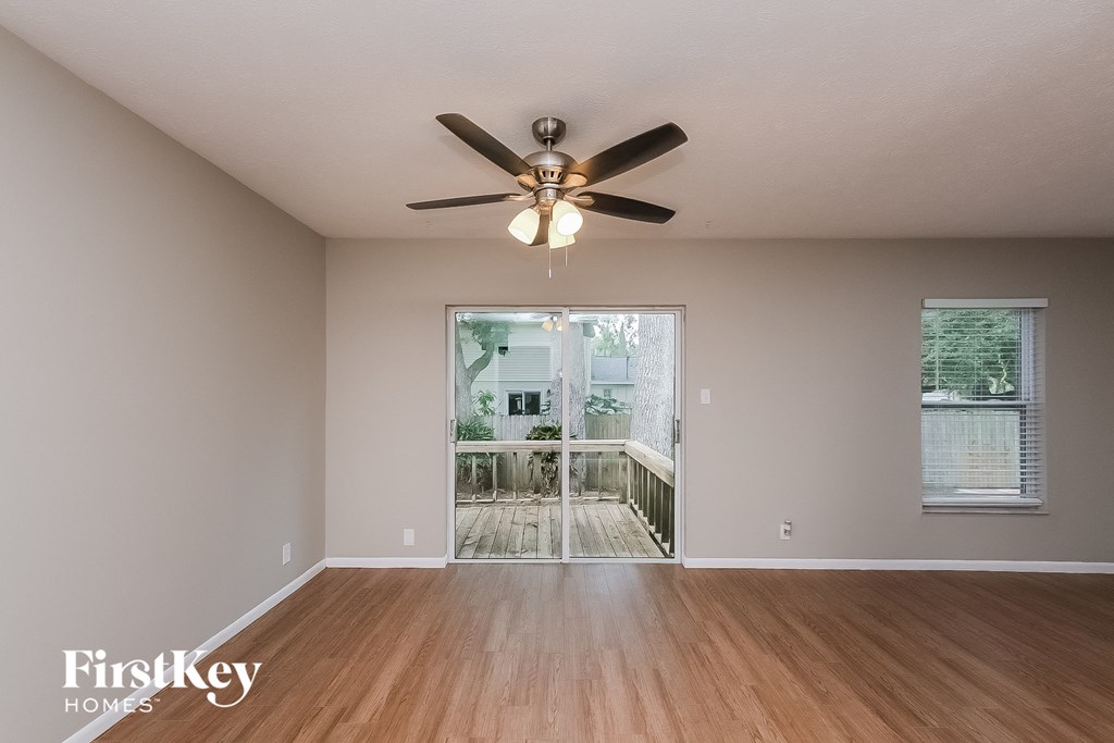 an empty living room with a ceiling fan and a deck