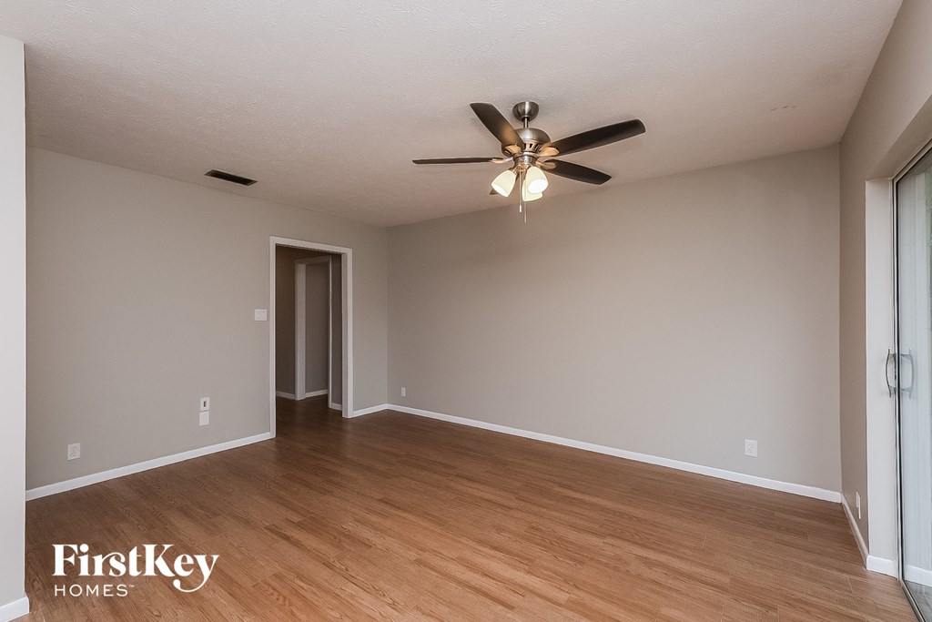 an empty living room with a ceiling fan and wood floors