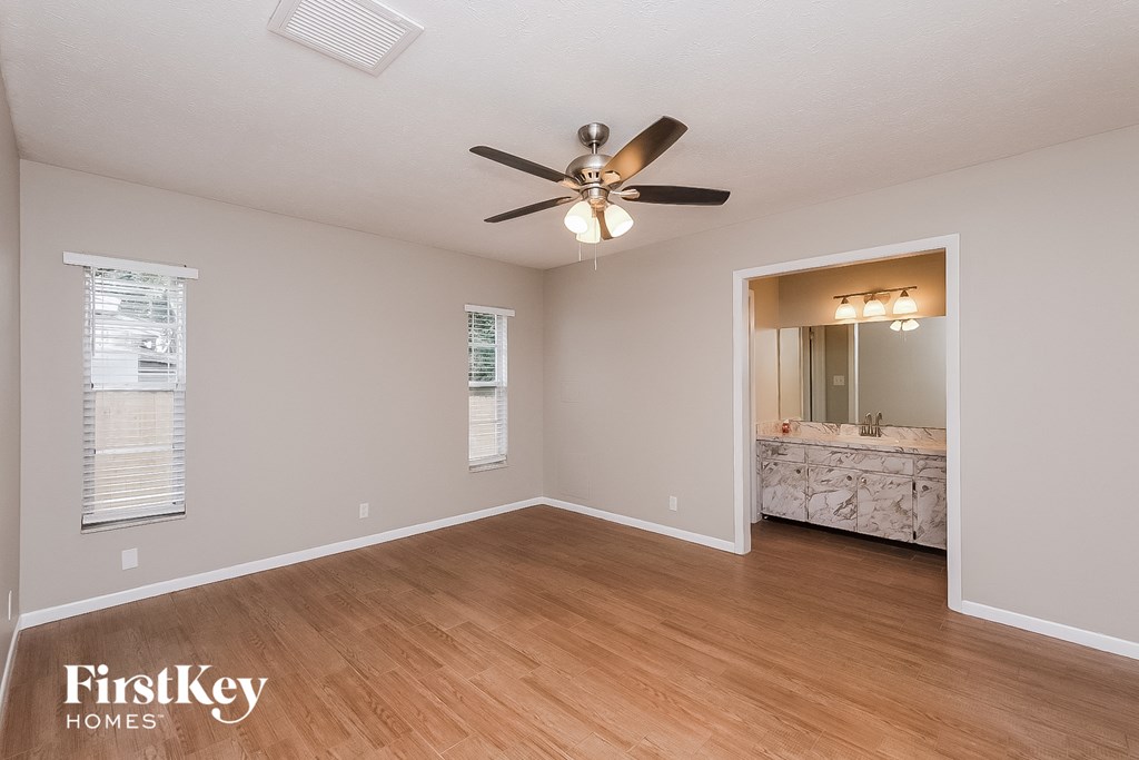 an empty living room with a ceiling fan and a bathroom
