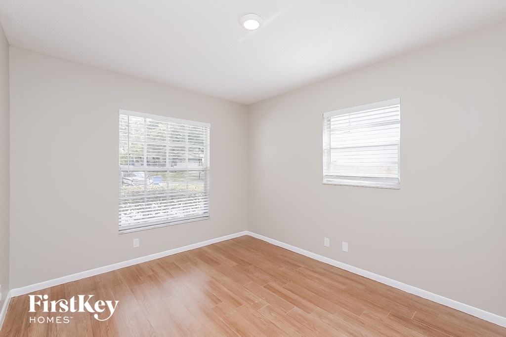 an empty room with wood floors and two windows