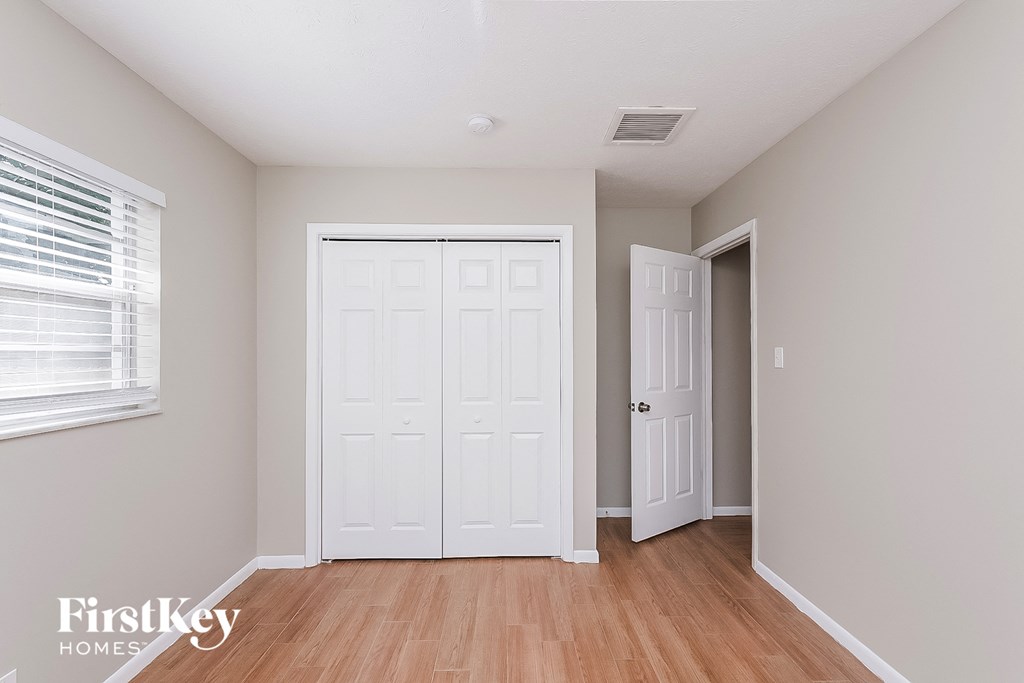the living room of a home with white doors and wood floors