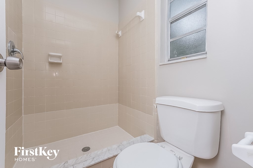 a bathroom with a toilet and a shower and a window