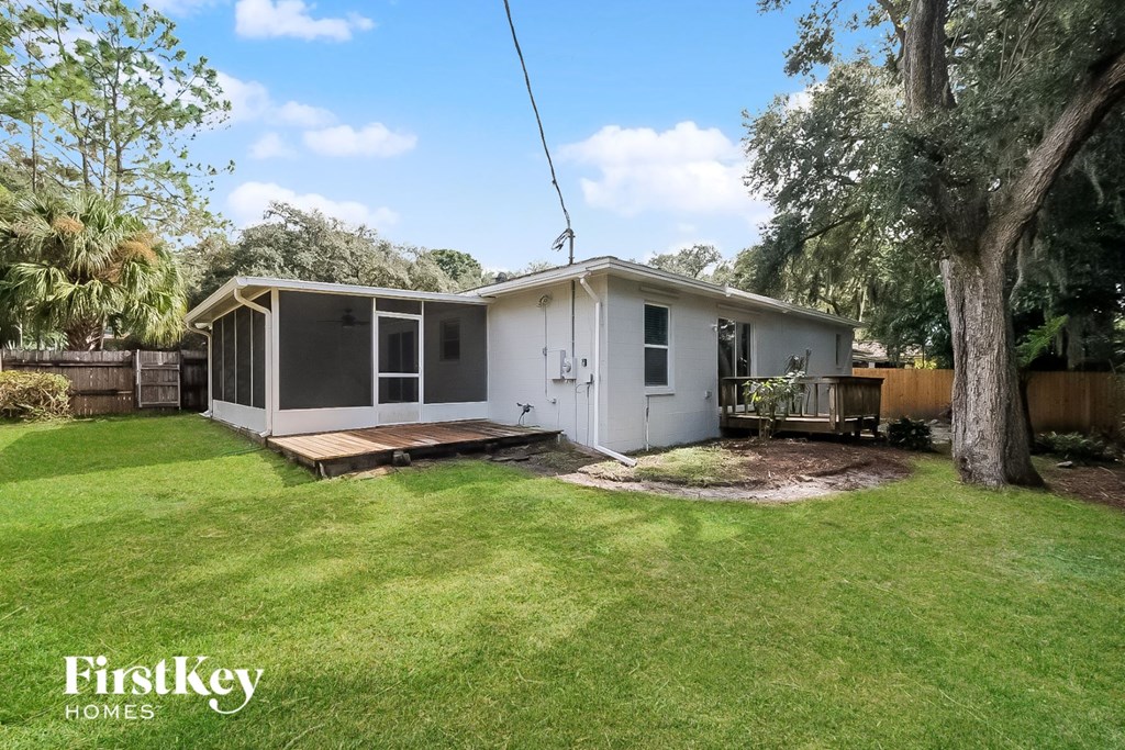 a small white house with a yard and a deck