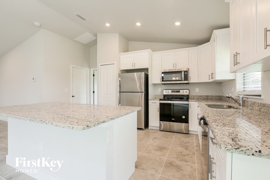 a white kitchen with granite counter tops and stainless steel appliances