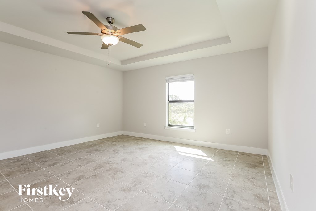 a clean and empty room with a ceiling fan and a window