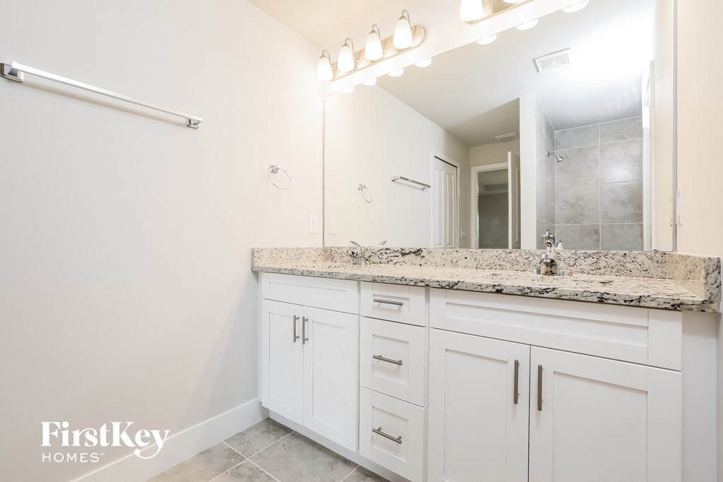 a bathroom with white cabinets and a sink and a mirror