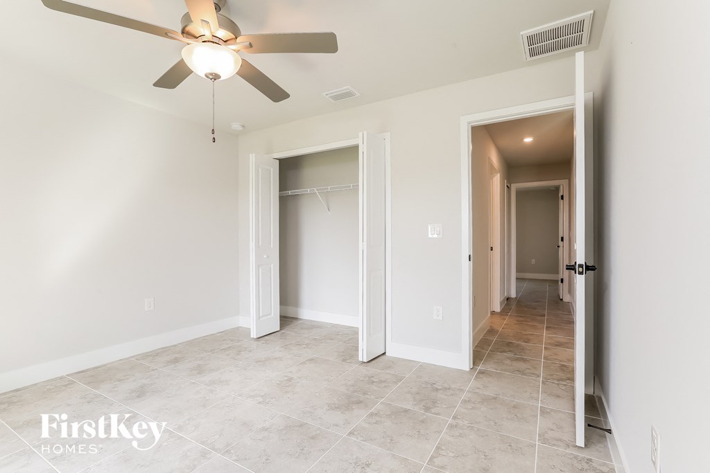 a bedroom with a ceiling fan and a hallway with a closet