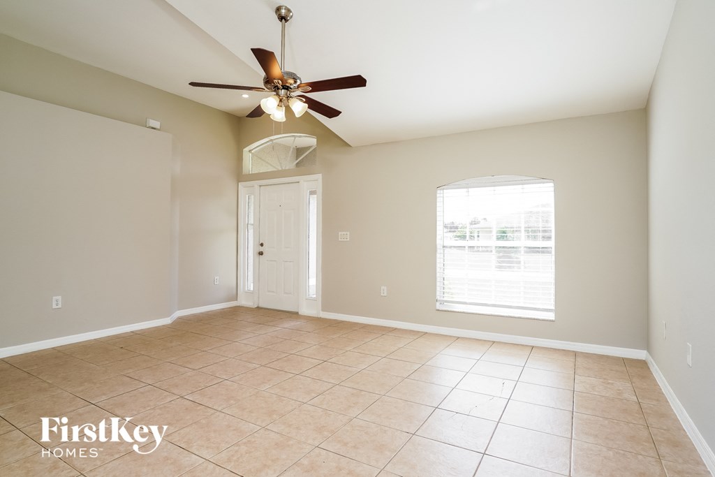 an empty living room with a ceiling fan and a window