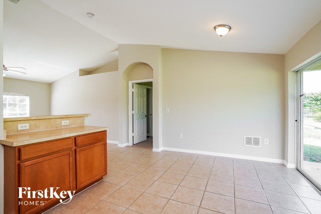 an empty kitchen with tiled flooring and a door to a hallway