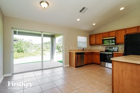 a kitchen with wooden cabinets and black appliances and a sliding glass door