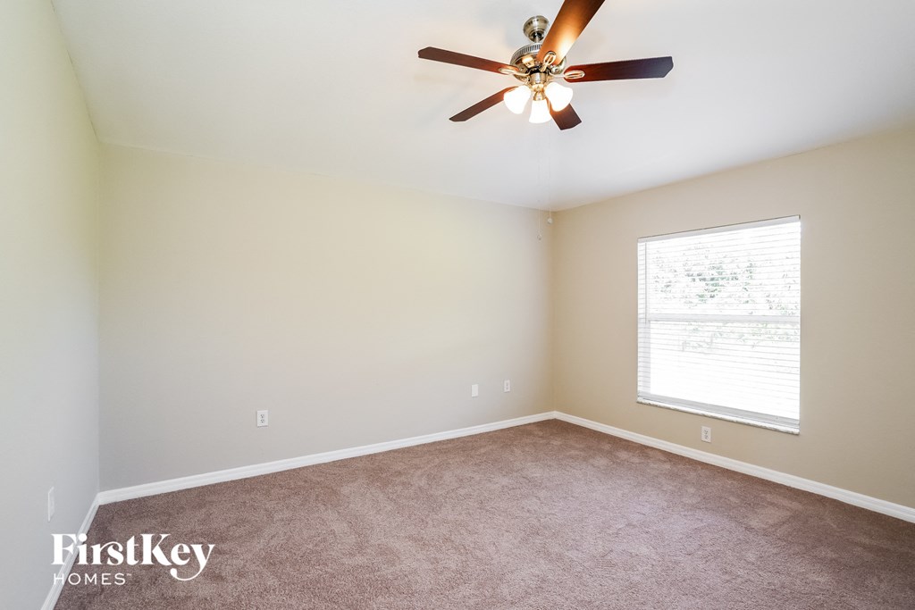 a carpeted room with a ceiling fan and a window