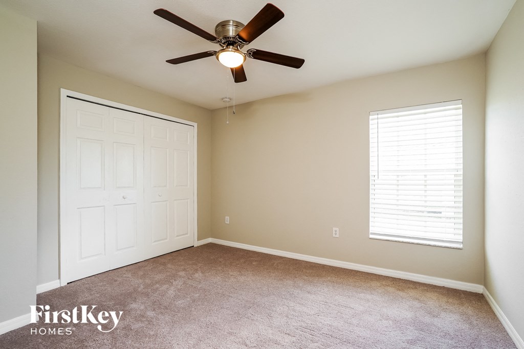a bedroom with a ceiling fan and a closet
