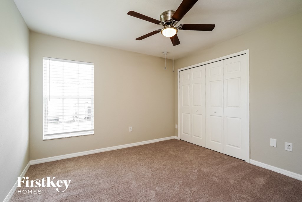 a bedroom with a ceiling fan and a closet
