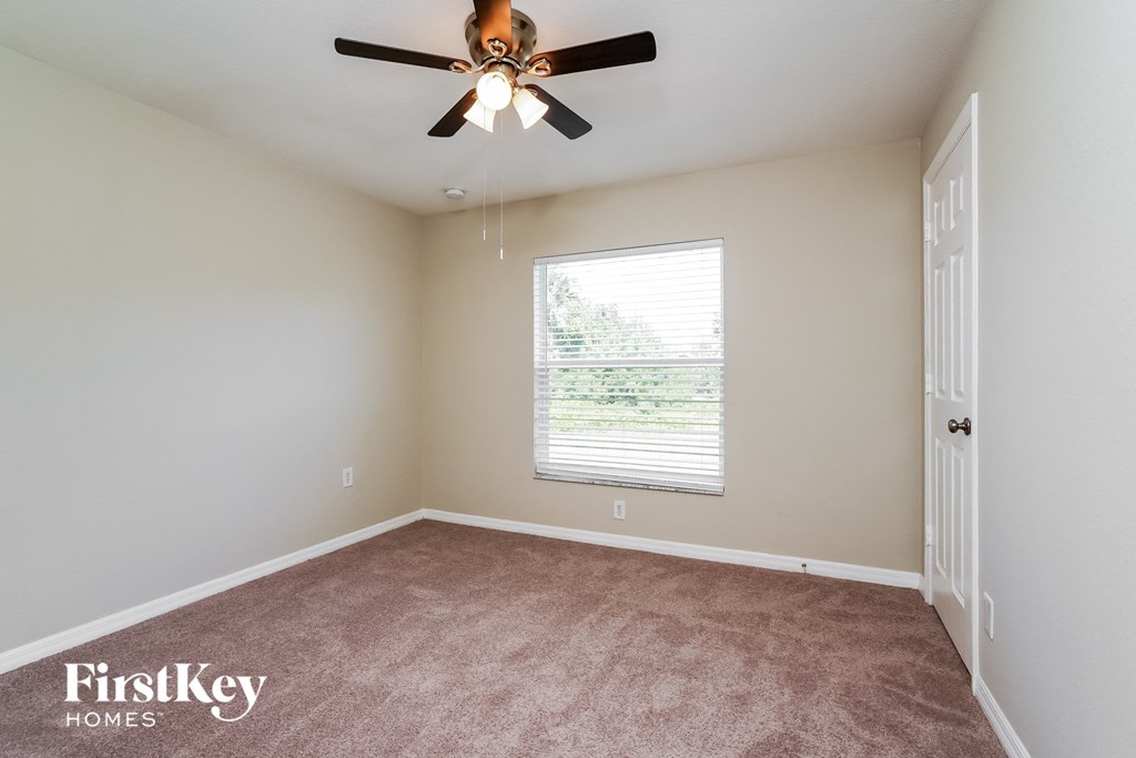an empty living room with a ceiling fan and a window