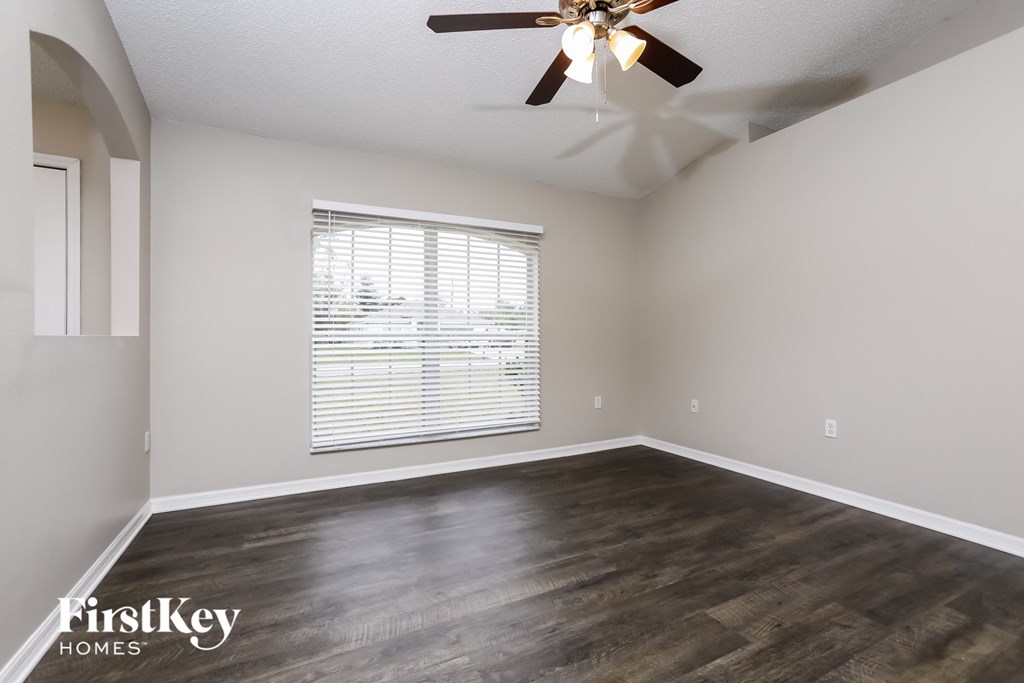 the spacious living room with a large window and a ceiling fan