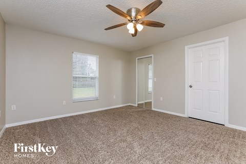 the spacious living room with ceiling fan and carpet