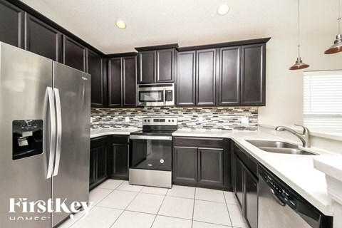 A kitchen with black cabinets and a stainless steel refrigerator.