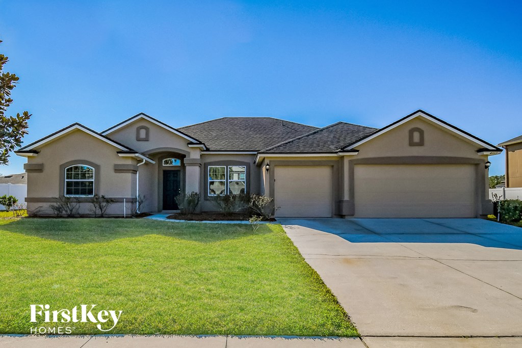 a beige house with a driveway and a lawn