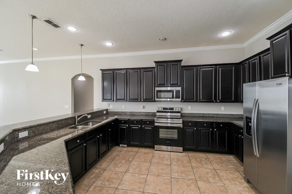 a kitchen with black cabinets and stainless steel appliances