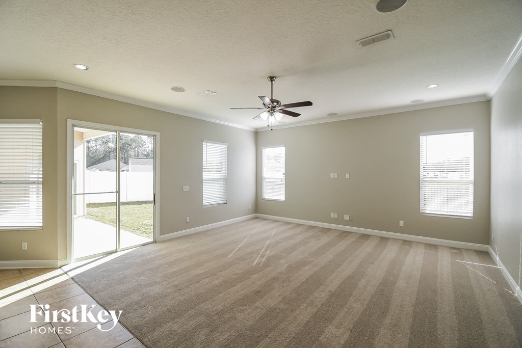 an empty living room with a ceiling fan and a window