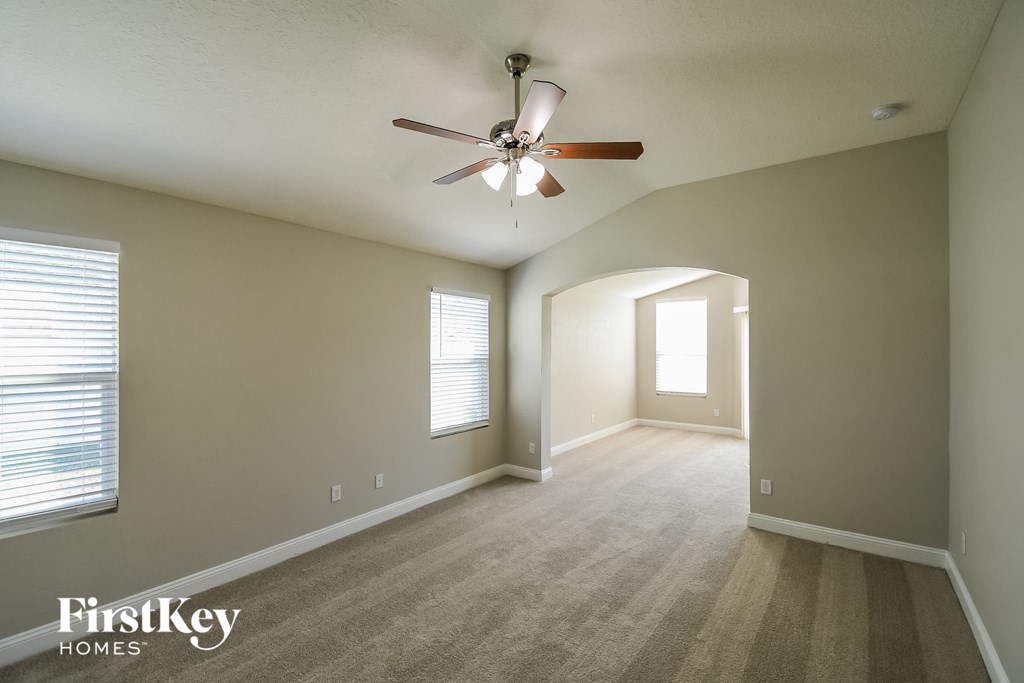 an empty living room with a ceiling fan and a window