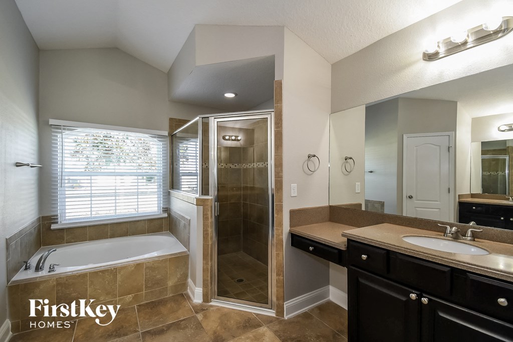 the master bathroom has a large walk in shower and a large vanity with a sink