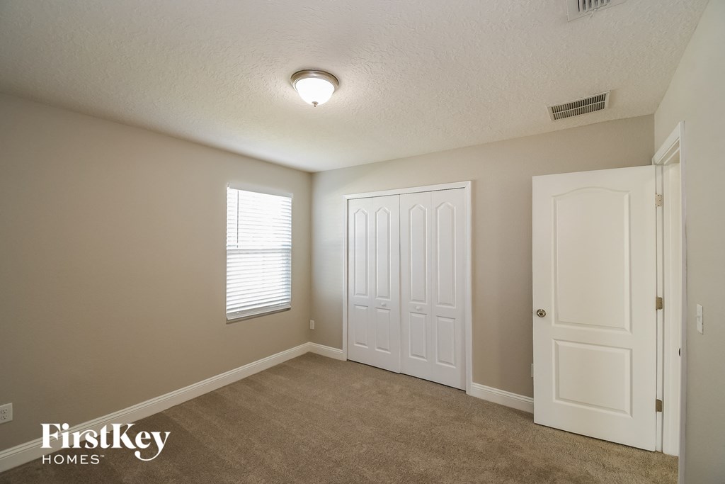a bedroom with a carpeted floor and a white door and window