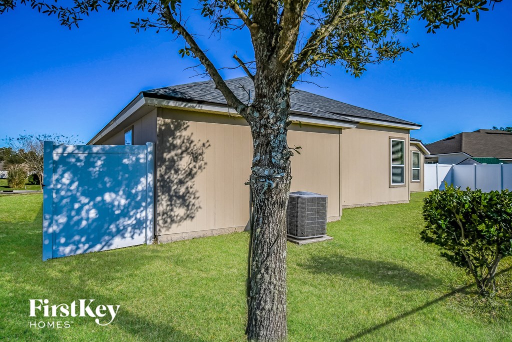 a beige house with a tree in the yard